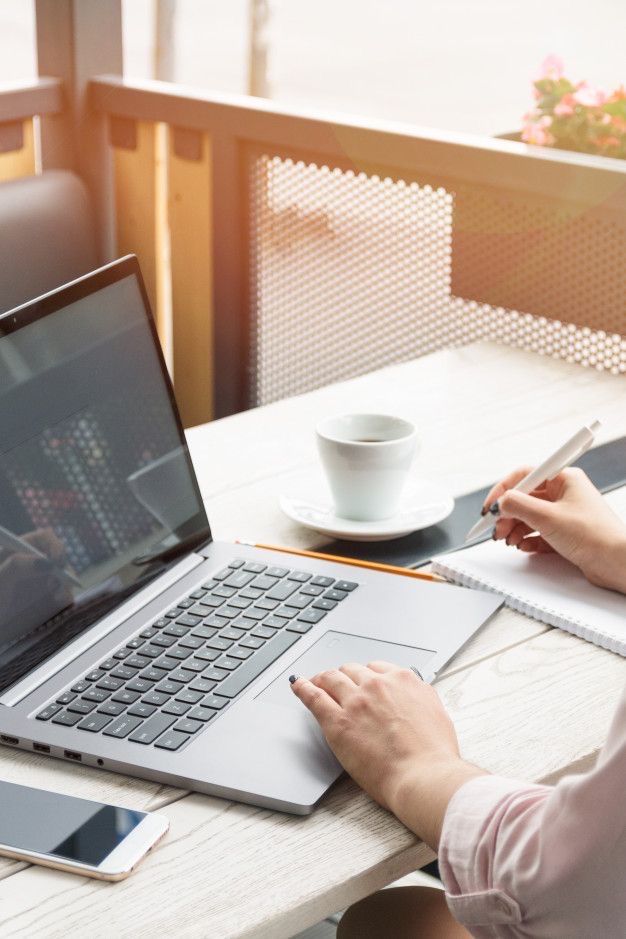 Person working on a laptop at a desk with a cup of coffee